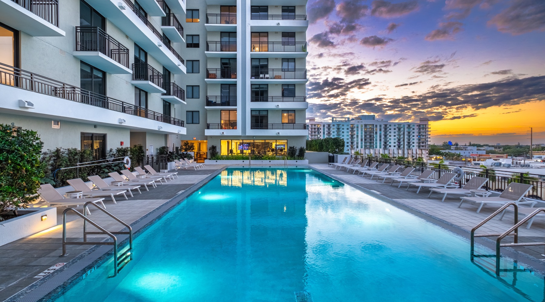 elevated pool deck with lounge chairs, overlooking the city, with the building in view