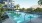 a swimming pool with chairs and umbrellas next to a building
