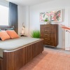 a bedroom with a nightstand, dresser and a window